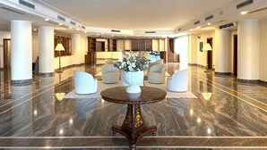 A spacious lobby with a marble floor, a round table with chairs, and a reception desk. - Naples Park Hotel (Marigliano)