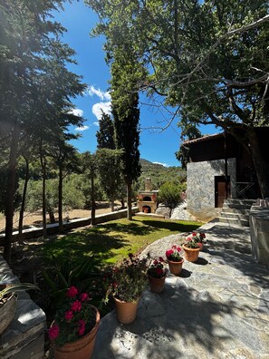 A stone patio with potted plants, a stone fireplace, and a view of a mountainous landscape. - Holiday Home 'Elis Studio Luxury Apartment' with Air Conditioning (ΙΕΡΑΠΕΤΡΑ)