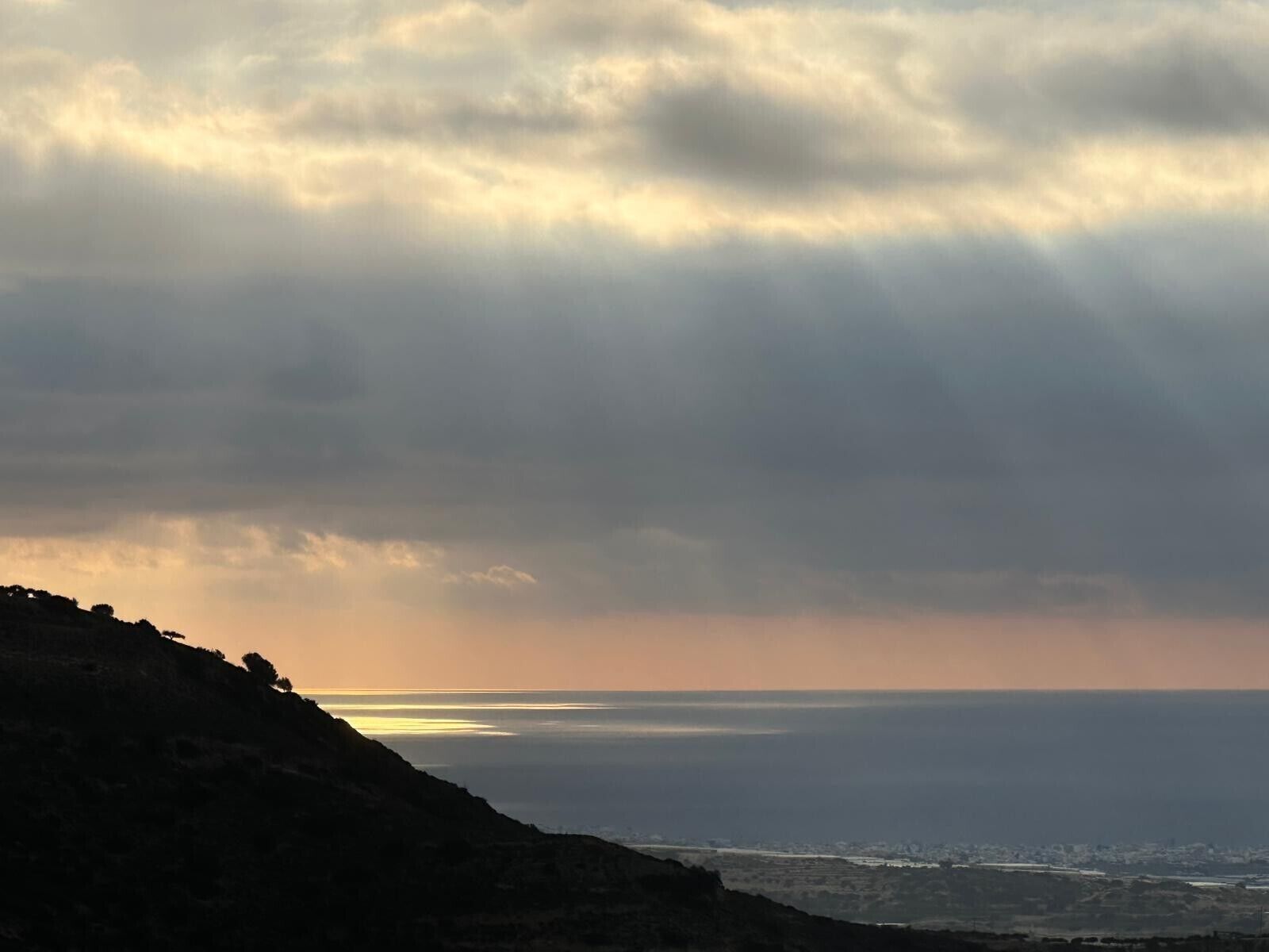 Eine Küstenlandschaft mit Blick auf das Meer und einer entfernten Skyline einer Stadt.