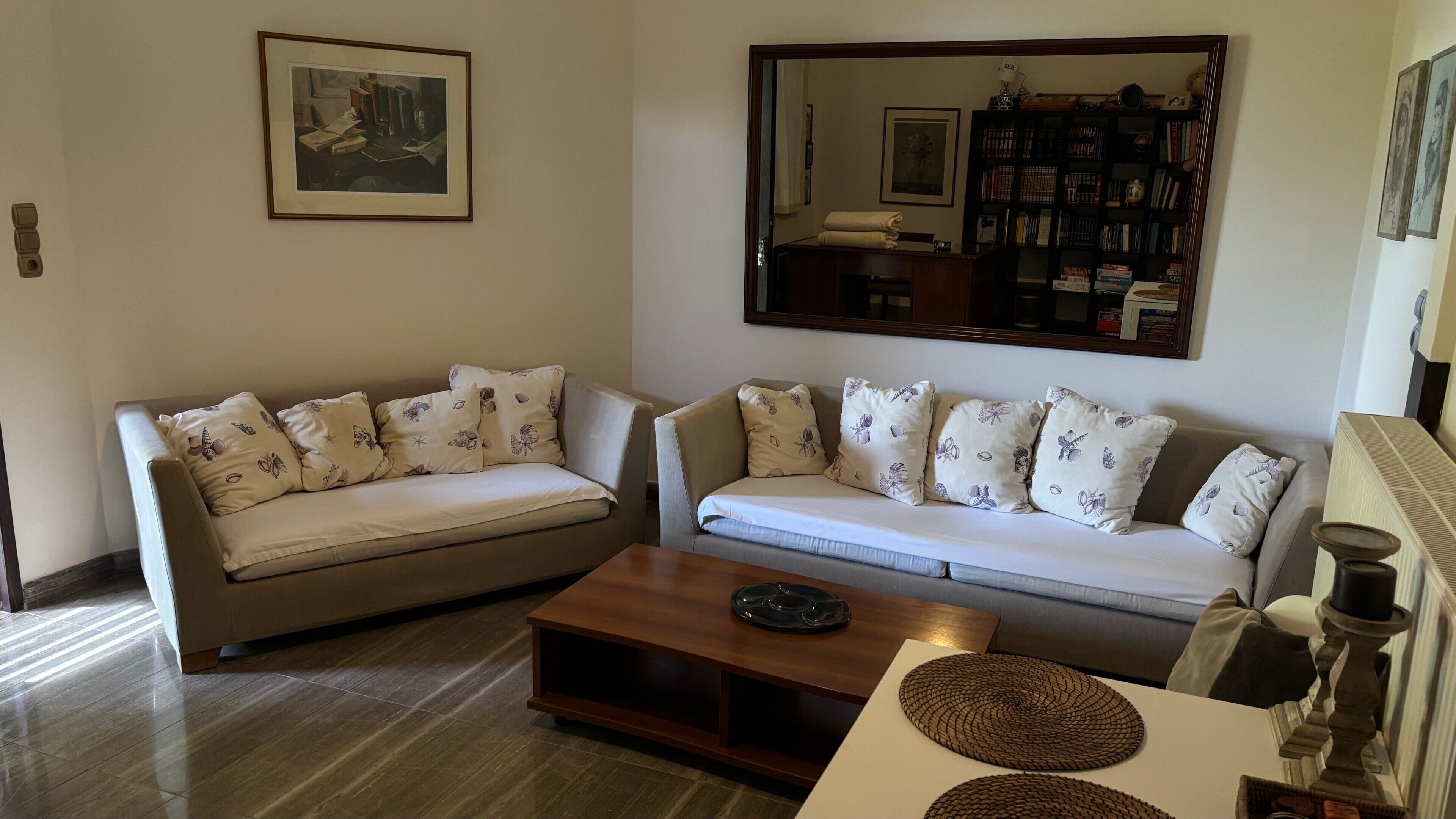 A living room with two sofas, a coffee table, a bookshelf, and a mirror.