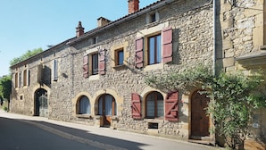 Un bâtiment en pierre doté de fenêtres en arc de cercle et d’une porte en bois.
