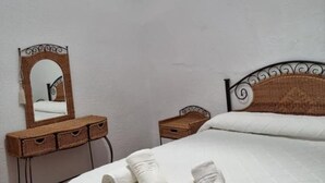A bedroom with a bed, a mirror, and a small table.