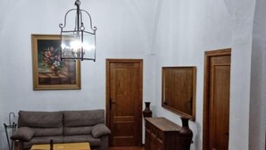 A room with a sofa, a wooden cabinet, a painting, and a door.