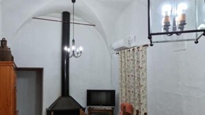A cozy living room with a fireplace, television, and a chandelier.