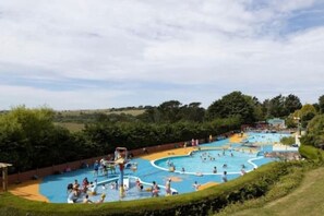 A large outdoor swimming pool with multiple lanes and a water slide, surrounded by greenery. - Charming Holiday Caravan – Your Perfect Getaway! (Newquay)