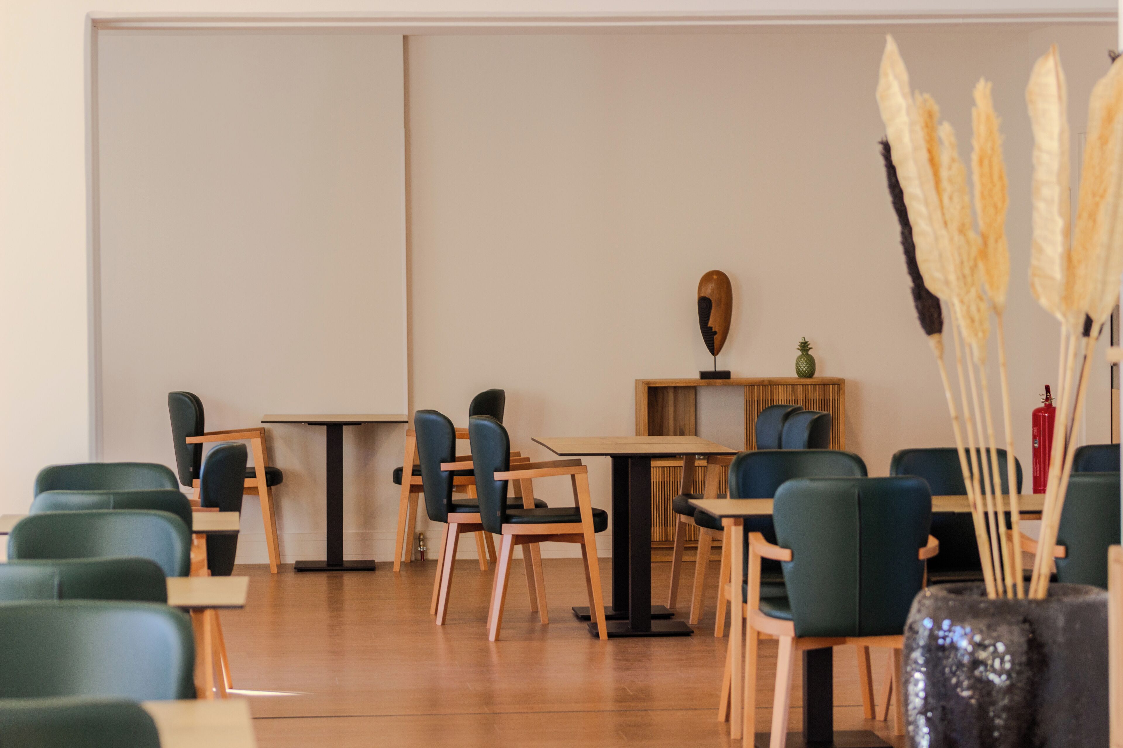 A modern dining area with green upholstered chairs and wooden tables.