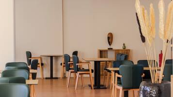 A modern dining area with green upholstered chairs and wooden tables.