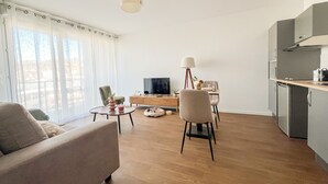Uma sala de estar moderna com um sofá, uma mesa de jantar e uma área de cozinha com armários e fogão.