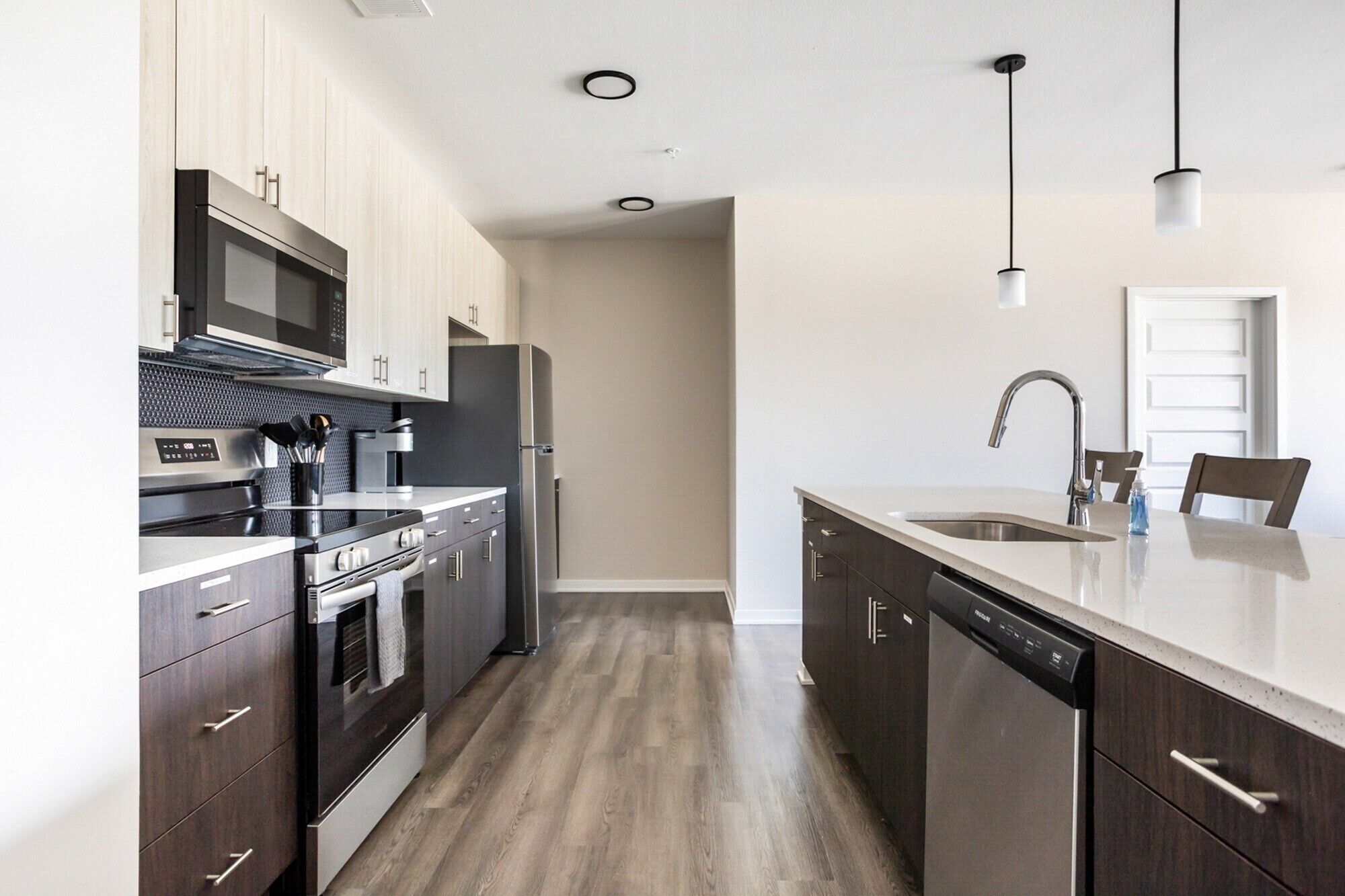 A modern kitchen with stainless steel appliances, wooden cabinets, and a central island with a sink.