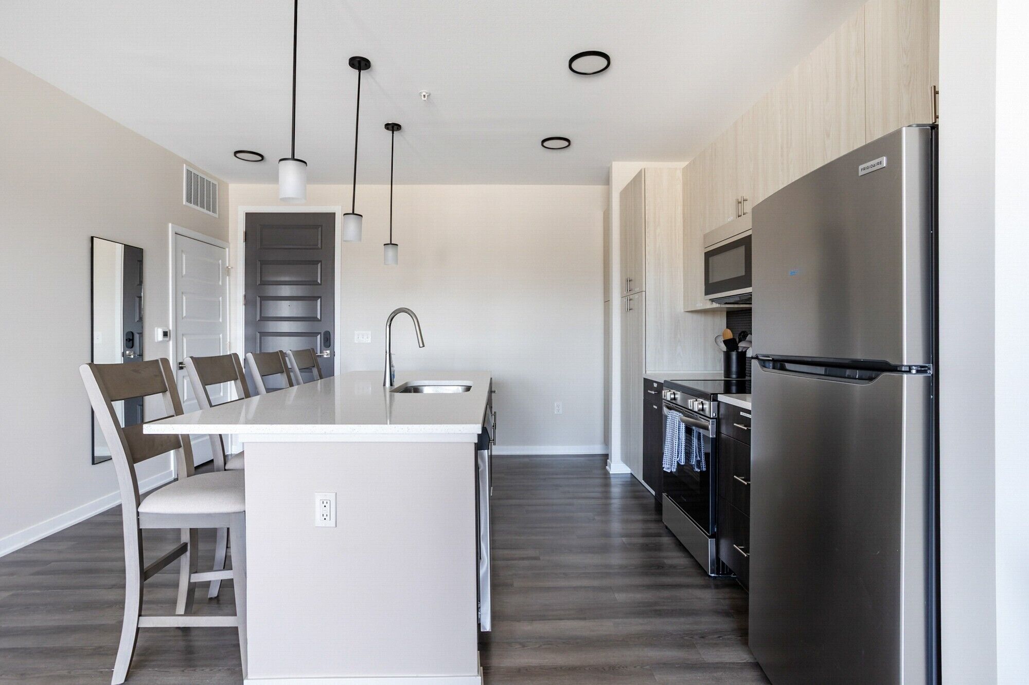 A modern kitchen with a central island, stainless steel appliances, and pendant lighting.