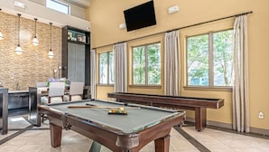 A pool table with billiard balls, a bar area with a counter and stools, and large windows with curtains. - Landing Amazing 1bd, Clubhouse, Gym (Houston)