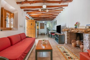 Una sala acogedora con un sofá rojo, vigas de madera, una chimenea y un televisor.
