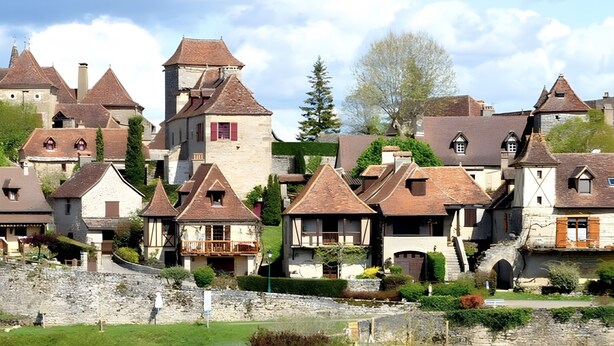 Een historisch dorp met traditionele architectuur, stenen muren en een rivier.