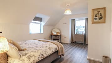 A bedroom with a bed, a desk, a chair, a window, and a door.