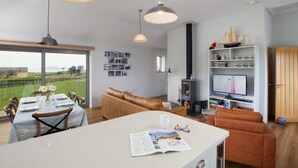 A spacious living area with a large dining table, a sofa, and a TV. - Sloopside - The Annexe, Bantham, South Devon (Bantham)