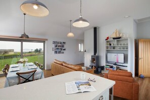 Ein geräumiger Wohnbereich mit großem Esstisch, einer Couch und einem Fernseher.
