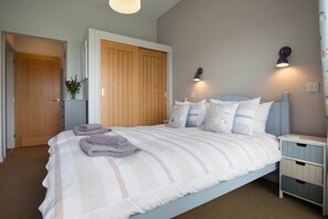 A bedroom with a bed, bedside tables, a wardrobe, and wall-mounted lights. - Sloopside - The Annexe, Bantham, South Devon (Bantham)