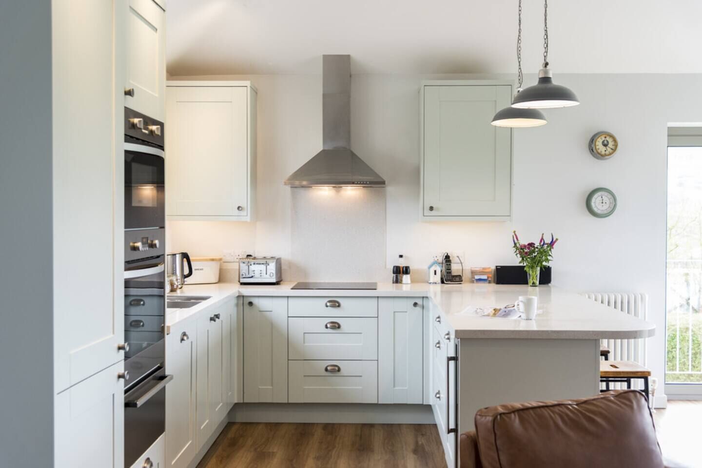 A modern kitchen with white cabinetry, a central island, and a hanging light fixture.