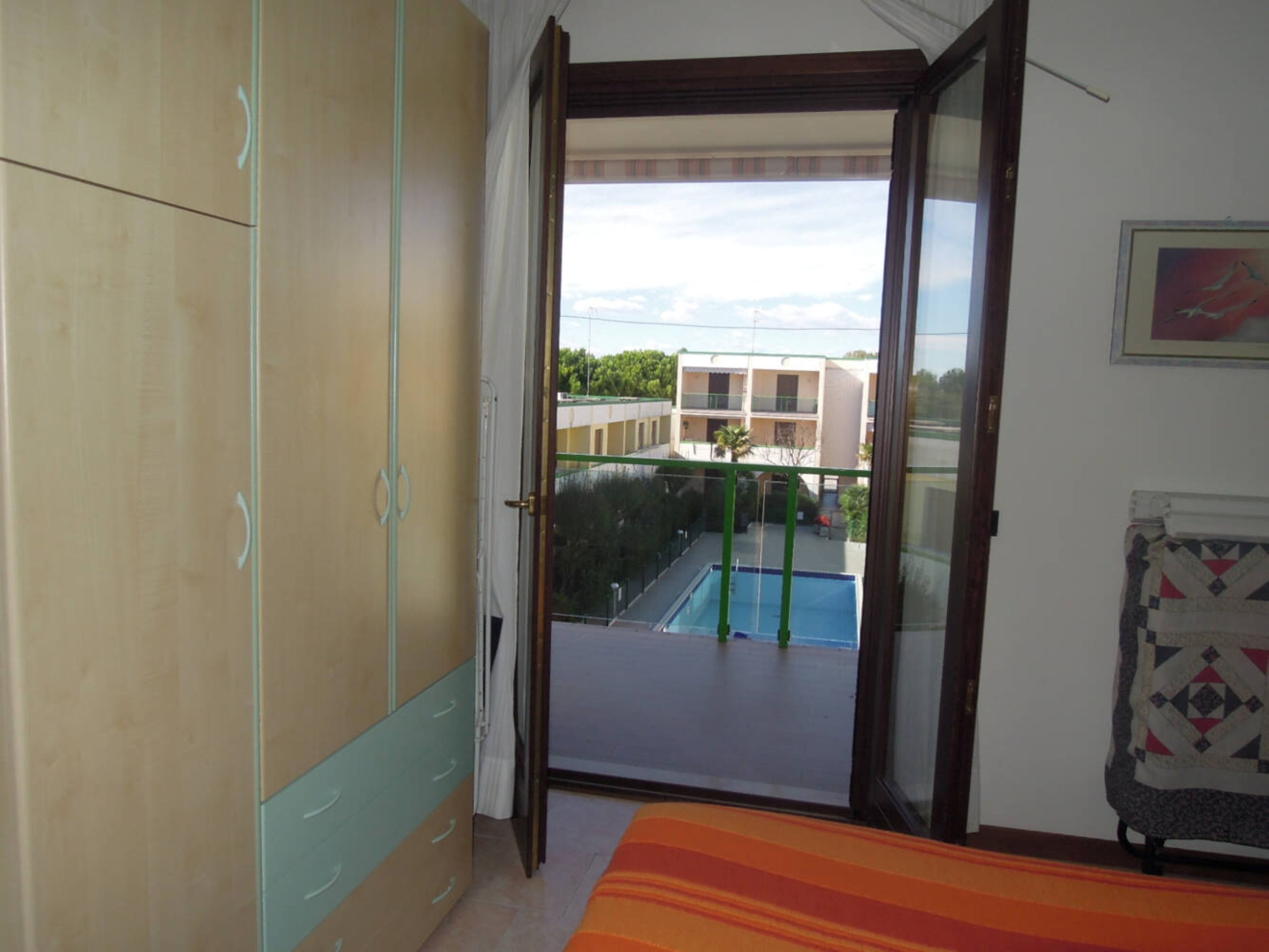 Et værelse med en skydedør til en balkon med en swimmingpool.