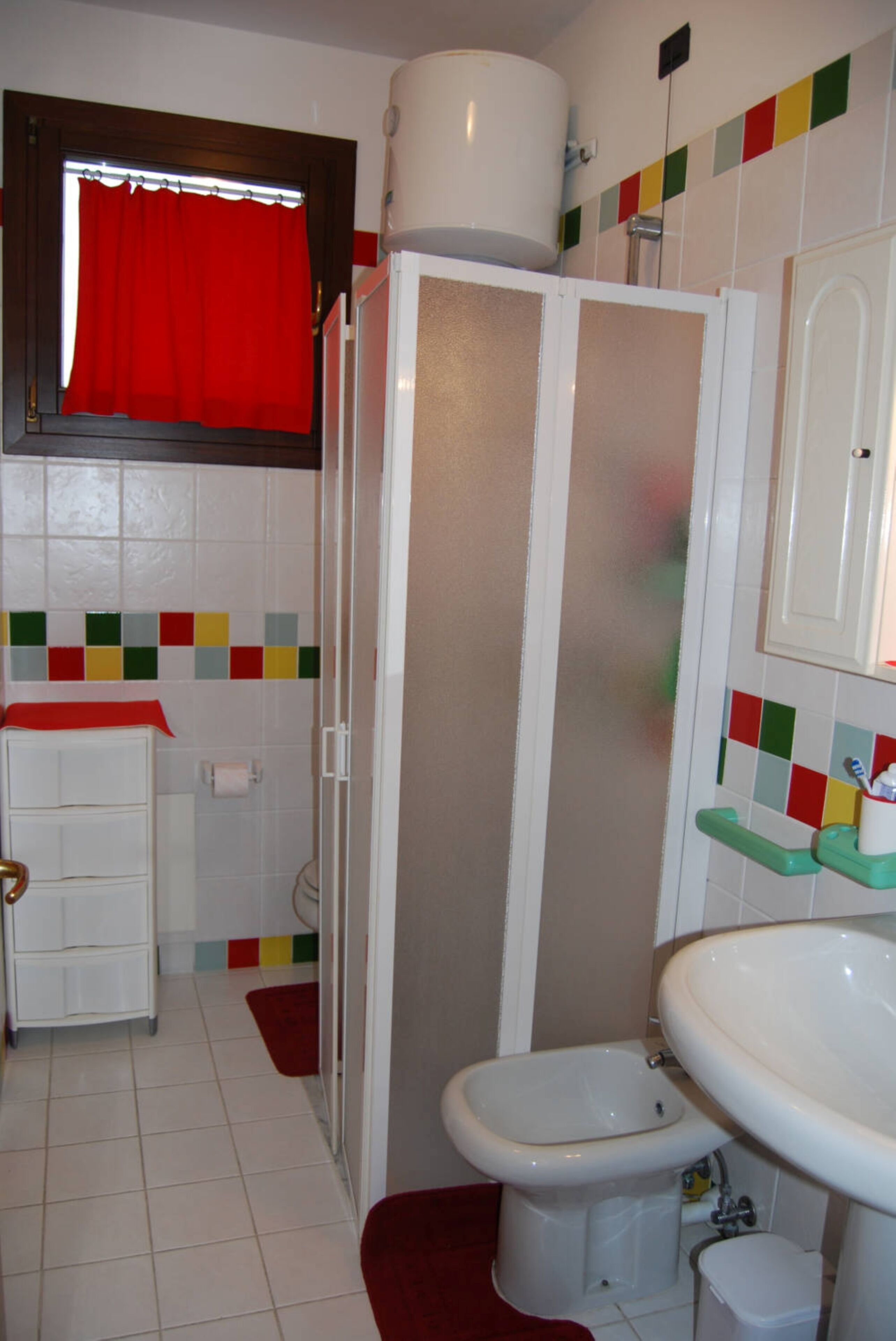 A bathroom with a toilet, bidet, sink, and a shower stall.