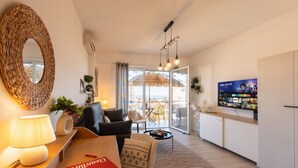A modern living room with a sofa, a coffee table, a TV, and a balcony with a view. - GuestHost - Modern Flat with Lovely Terrace (Sanremo)