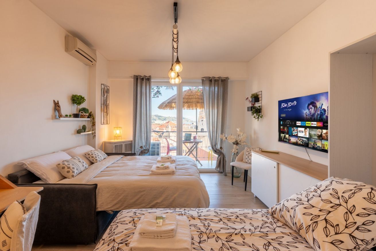 Een hotelkamer met twee bedden, een televisie, een balkon en uitzicht op de stad.