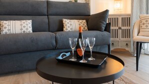 A modern living room with a grey sofa, a round coffee table, and a bottle of Prosecco on a tray. - GuestHost - Modern Flat with Lovely Terrace (Sanremo)