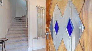A staircase with a handrail, a door with a geometric design, and a small table. - Retro Art Deco 2Bed with Parking in Thames Ditton - Pass the Keys (Surrey)
