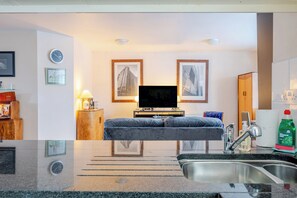 A modern hotel room with a bed, a TV, a sink, and framed pictures on the wall. - Retro Art Deco 2Bed with Parking in Thames Ditton - Pass the Keys (Surrey)