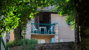 A house with a balcony, a stone wall, and a tree in the foreground. - Cottage for 4 People (La Canourgue)