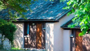 A house with a sloped roof, a wooden door, and a small porch area. - Cottage for 4 People (La Canourgue)