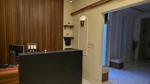 Un espace d’accueil avec un mur revêtu de panneaux en bois, un comptoir d’accueil et des luminaires suspendus.