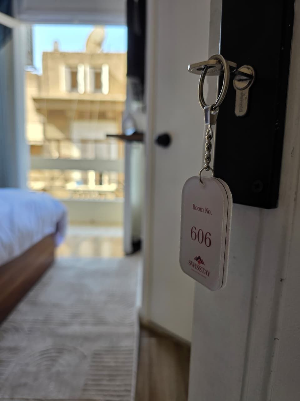 Un llavero con el número de habitación 606 y el logotipo de SwissStay, que indica una habitación de hotel.