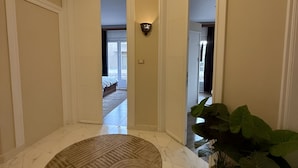 Un couloir doté d’un sol en marbre, d’un tapis rond et d’une plante en pot.