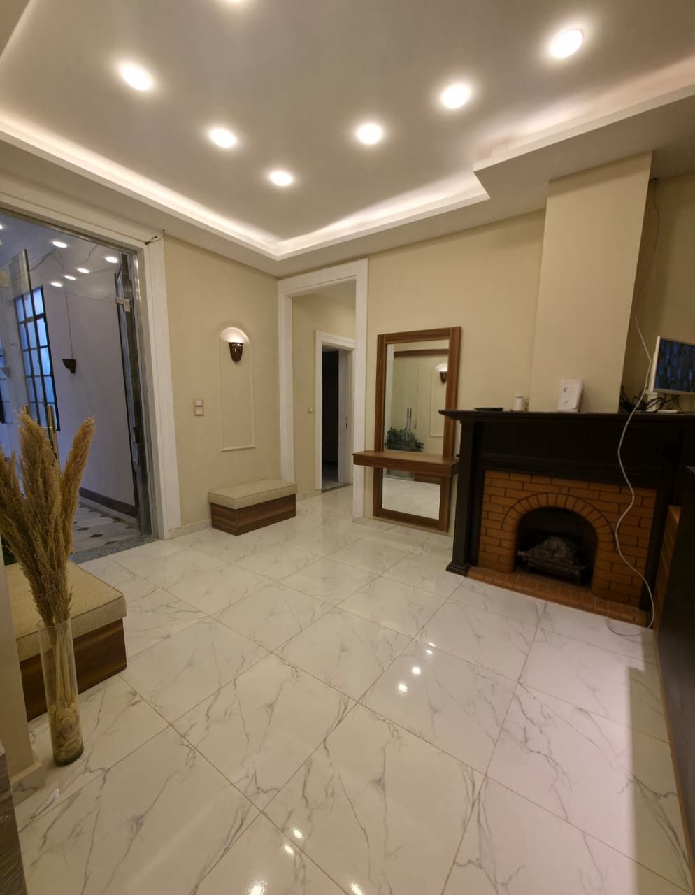 A spacious living room with a fireplace, a large mirror, and a modern design.