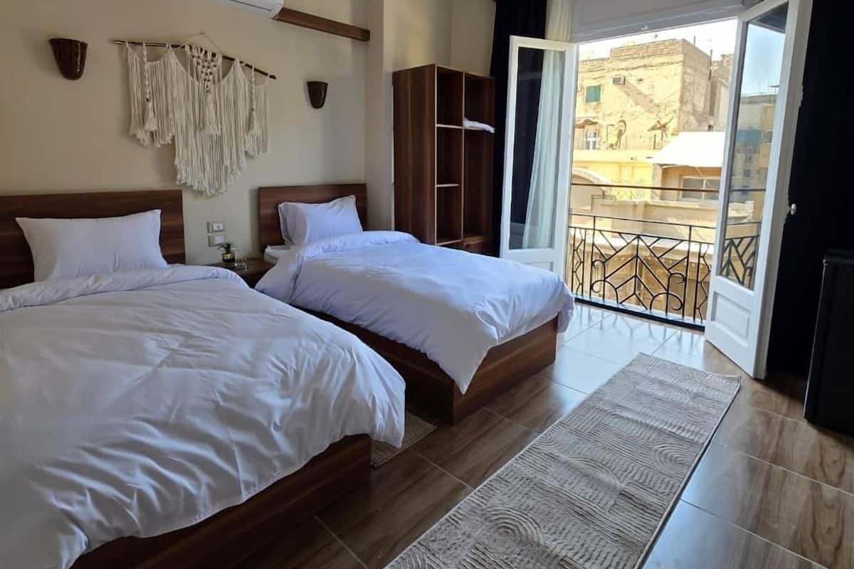 A hotel room with two beds, a large window, and a balcony.