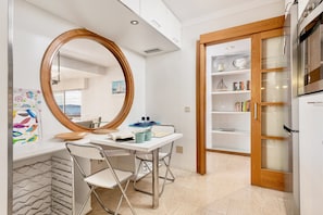 A modern kitchen with a white countertop, a wooden-framed mirror, and a built-in bookshelf. - Ancora - Frontline Apartment with Stunning Views (Port de Pollença)