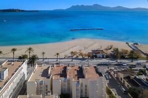 A coastal cityscape with a beach, palm trees, and buildings. - Ancora - Frontline Apartment with Stunning Views (Port de Pollença)