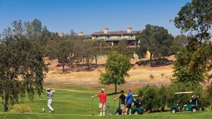 Um campo de golfe com um clube de campo ao fundo.