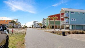 A street with multi-story buildings, a parked car, and a clear sky. - 40th Street Cottage (Port St. Joe)