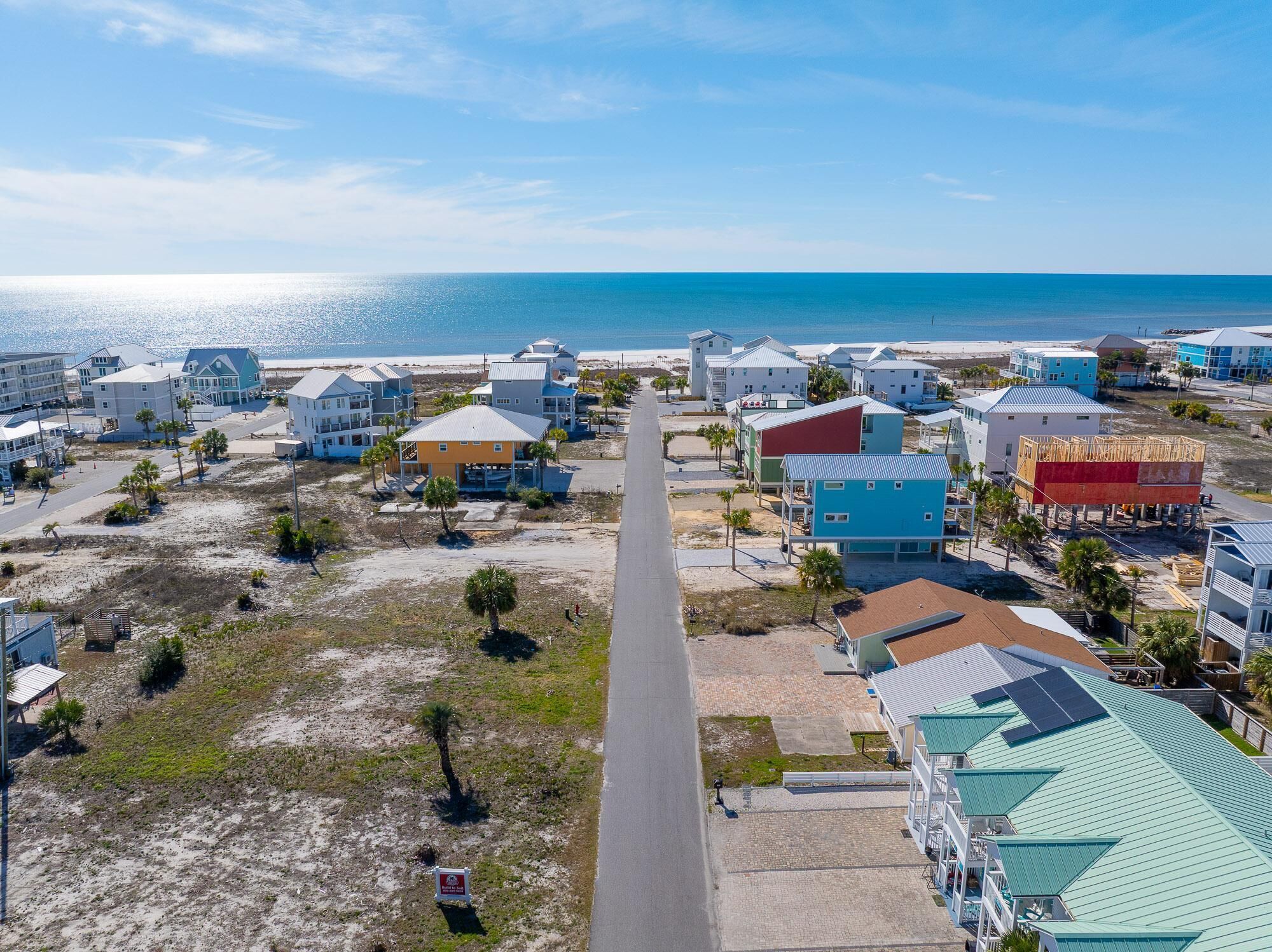A coastal residential area with houses, a beach, and a clear sky.