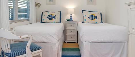 Ein Schlafzimmer mit zwei Betten, einem Nachttisch, einem Sessel und einer Fisch-Wanddekoration.