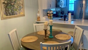 A dining area with a round table, white chairs, and a chandelier. - The Hil & Dale: Wayside Forest UNIT 12. Entire Townhouse. Pets welcomed! (Murrells Inlet)