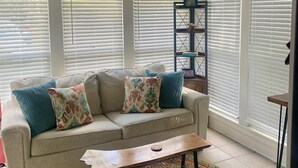 A room with a beige sofa, colorful pillows, a wooden coffee table, a patterned rug, and a ceiling fan. - The Hil & Dale: Wayside Forest UNIT 12. Entire Townhouse. Pets welcomed! (Murrells Inlet)