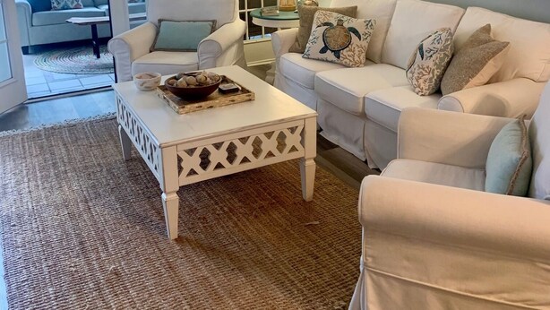 A living room with a white sofa, a coffee table, and a patterned rug. There are framed pictures on the wall and a lamp on a side table. - The Hil & Dale: Wayside Forest UNIT 12. Entire Townhouse. Pets welcomed! (Murrells Inlet)