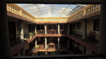 A multi-level atrium with a glass ceiling, columns, and potted plants.