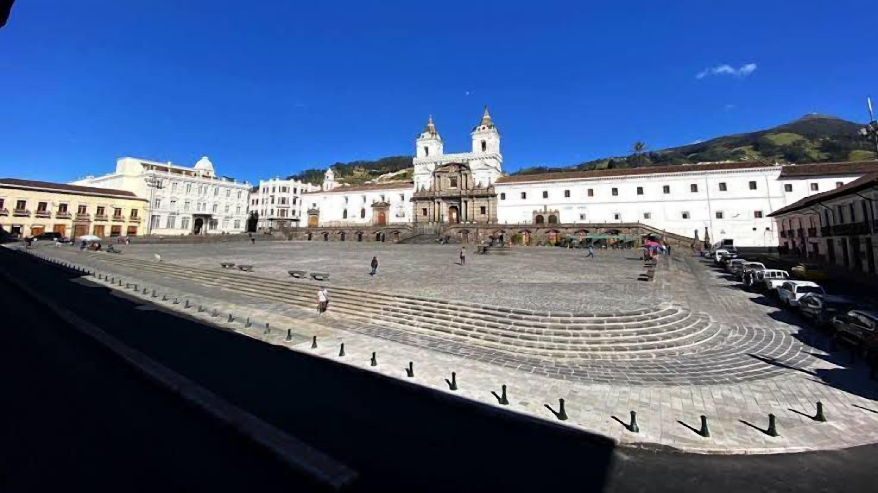 A large open plaza with a central staircase leading to a building with two towers.