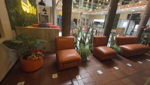 A lobby with seating areas, potted plants, and a reception desk. - Hostal Viena Internacional (Quito)