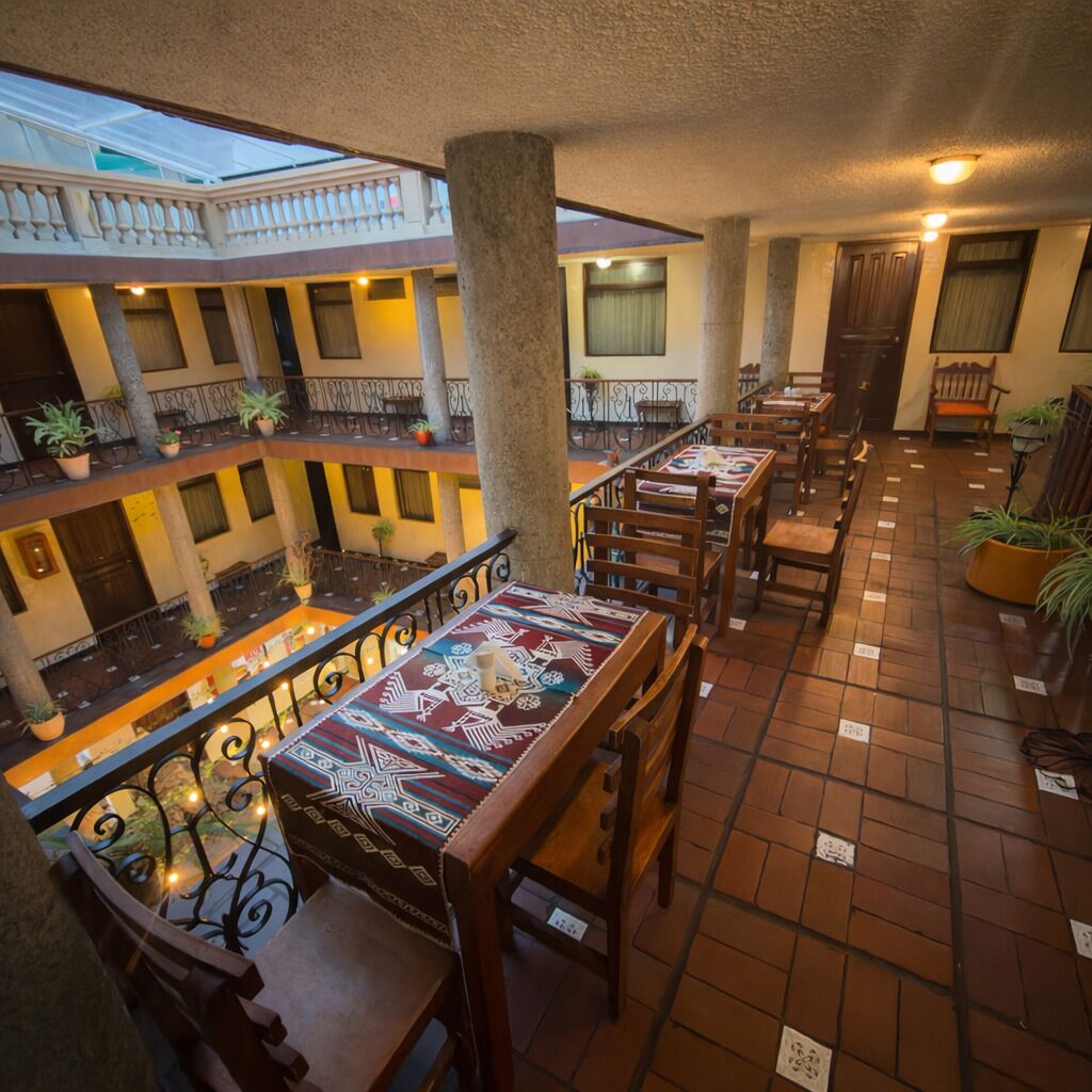 A multi-level dining area with tables and chairs, a balcony with potted plants, and a view of the building's interior.