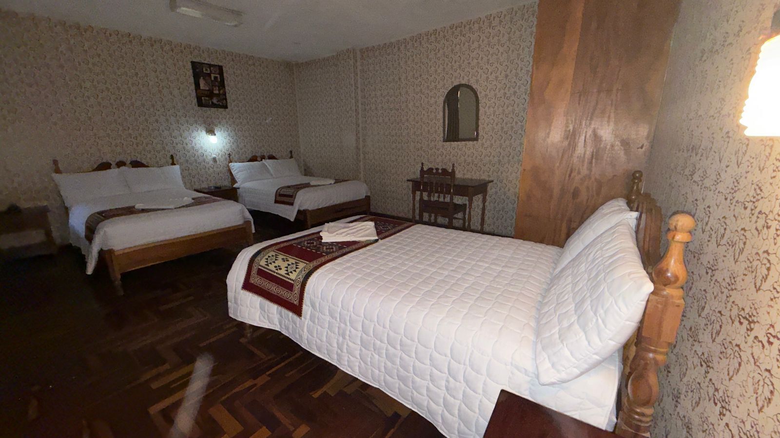 A room with two beds, a wooden chair, and a small table.